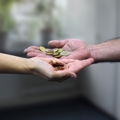 Eine Frauenhand hält Cent- und Zehn-Cent-Münzen, eine Männerhand Ein- und Zwei-Euro-Münzen in der Hand.