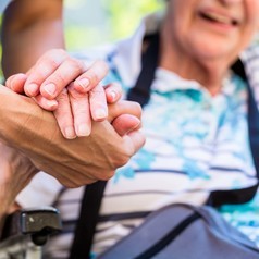 Eine Pflegerin hält die Hand einer älteren Frau.