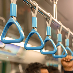 An blauen Haltegriffen in einer Straßenbahn hält sich ein Mann fest.
